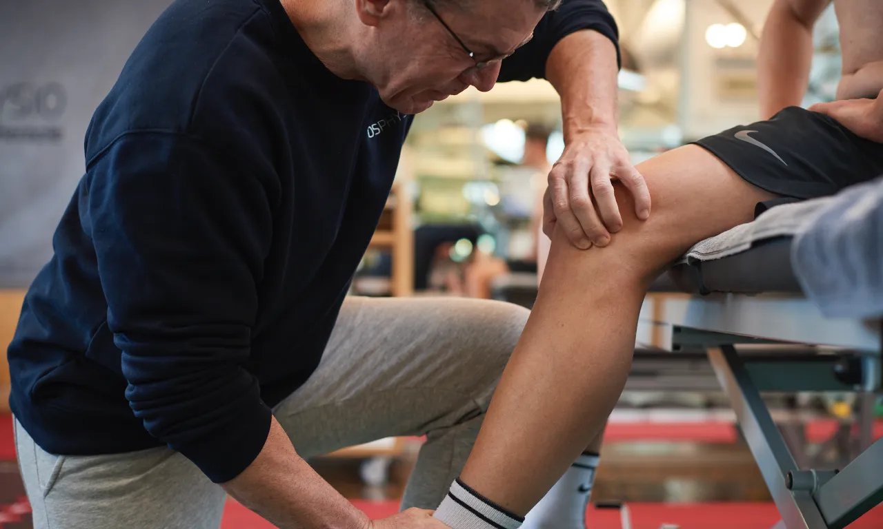 Physiotherapeut untersucht Knie eines Patienten