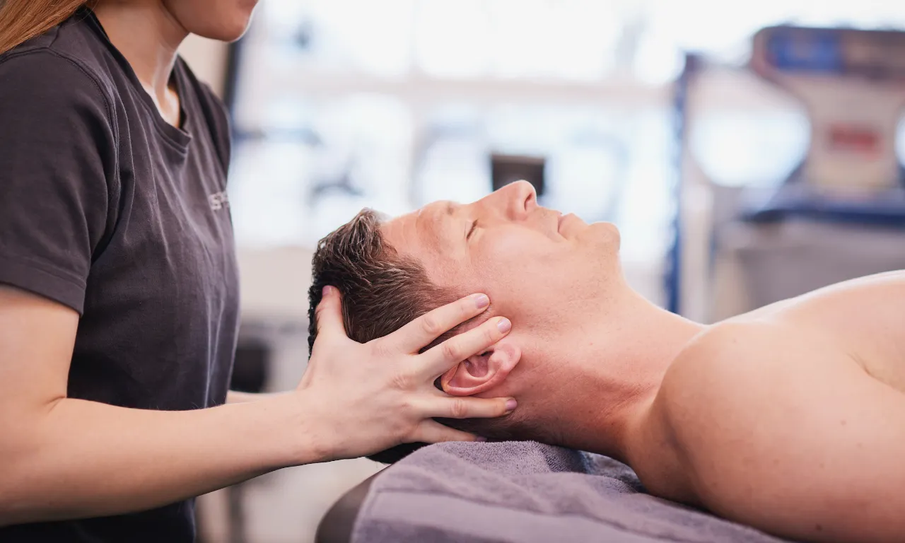 Ein Physiotherapeut behandelt einen Patienteb am Kopf.